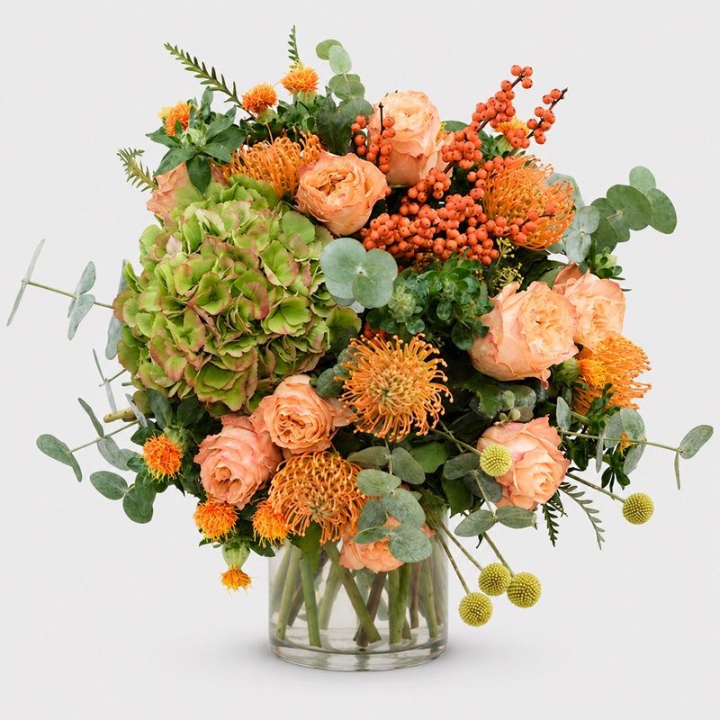 Buchet floral de lux cu hortensie, trandafiri somon, leucospermum, hypericum și eucalipt, în nuanțe naturale de verde și portocaliu.